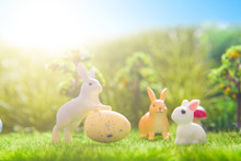 Colorful Easter Eggs And Rabbits Toys On Green Grass. Fairy Tale