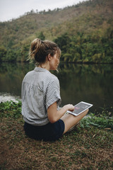 Wall Mural - Woman alone in nature using a digital tablet with entertainment application