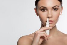 Portrait Of Tranquil Young Woman Treating Her Runny Nose By Spray. She Is Standing With Naked Shoulders. Isolated And Copy Space