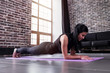 © undrey - Young sportswoman working-out at home doing plank exercise on yoga mat