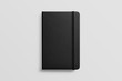 © PrimeMockup - Photorealistic black leather notebook mockup on light grey background, front view.