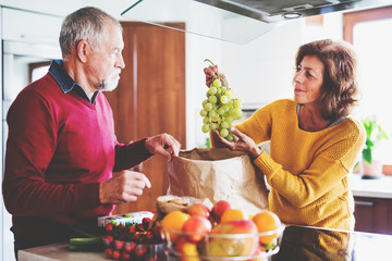 Poster - Senior couple unpacking fruit in the kitchen.