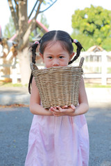 Wall Mural - Adorable little asian girl holding a basket outdoors in the farms.