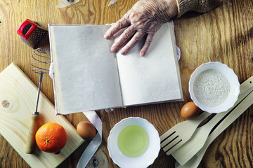 Wall Mural - Open recipe book in the hands of an elderly woman