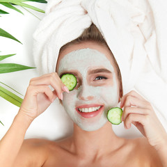 Portrait of beauty woman laying with towel on the head, cucumber on her eyes, facial mask. Spa therapy. Relax.