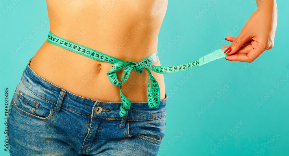 Woman measuring her waist over white background. Wellness concept - obrazy, fototapety, plakaty 