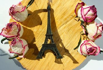 Eiffel tower sovenir among flowers on wooden background