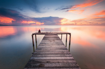  wooden jetty toward horizon during sunset with reflection.