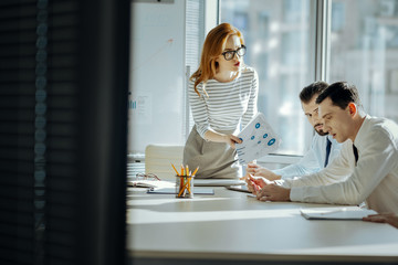 Wall Mural - This is unacceptable. Beautiful young female boss scolding her employees for a poor performance, showing them documents indicating profit loss