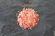 Pile of pink Himalayan salt. Top view on a dark stone background.
