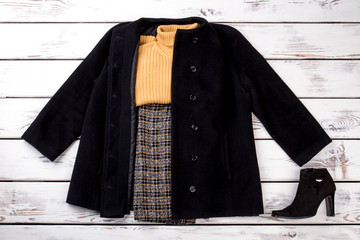 Wall Mural - Winter women outfit with yellow woolen sweater. Checkered trousers and pullover in black coat. Suede heel boot, side view.