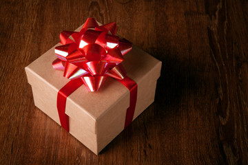 Wall Mural - One festive gift box with a red bow on a wooden table