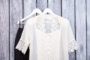 Wall Mural - Hollow crochet white lace blouse and trousers. Dark wooden desk surface background.