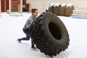 Wall Mural - Young sporty woman flipping heavy tire, outdoors