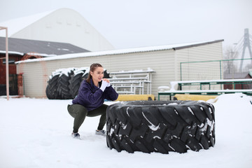 Wall Mural - Young muscular woman training on heavy tire, outdoors