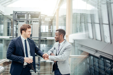 image of two multiracial businessmen handshaking in modern office for end of great deal