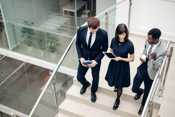 team business people wear suit and walking down on step of stair and holding smartphone and tablet