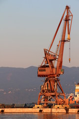 Summer morning view of tall red port crane in empty harbour at sunrise with Ucka mountain ridge Istrian Peninsula in background, Rijeka city Croatia Adriatic Sea Kvarner Gulf Balkan Peninsula Europe