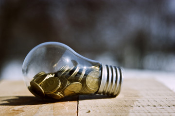 Lamp with coins on a wooden table close-up