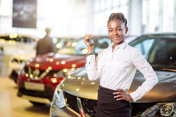 african american woman with her new car showing key