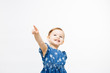 A very excited and happy toddler girl pointing up with one finger, isolated on white studio background