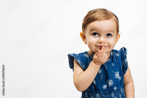 Photographie Make a wish - Small child with finger on mouth looking up, isolated on white bac
