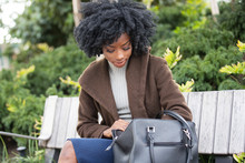 Beautiful African American Woman With Black Curly Hair Looking In Her Purse