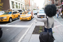 Woman Hailing A Taxi Cab On A Busy City Street
