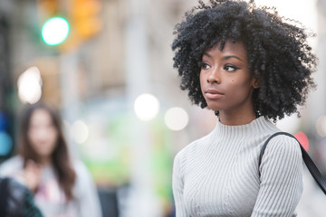 Pretty woman with black curly hair outside in city