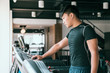 © PR Image Factory - Male runner set up treadmill in gym