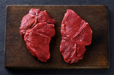 Wall Mural - Fresh raw beef steaks on a dark wooden background.