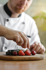 Closeup of a concentrated male pastry chef decorating dessert in the kitchen