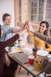 © zinkevych - This is success. Nice positive delighted people sitting around the table and giving high five while showing their team spirit