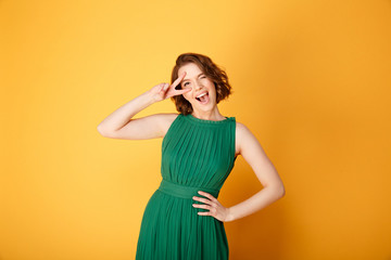 portrait of young pretty woman showing peace sign isolated on orange