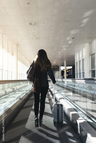 Plakat Unrecognizable kobiety odprowadzenie z walizką w lotnisku.