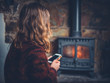 © LoloStock - Woman using smart phone by the fireplace