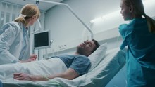  Emergency In The Hospital, Doctor And Nurse Rush Into The Ward To Safe Dying Patient. Man Is Lying On The Bed Without Signs Of Life. Doctors Do Everything To Resuscitate Him.