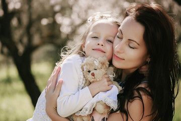 baby girl and her mother in the garden with blooming almonds