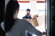 © Halfpoint - Woman receiving parcel from delivery man at the door.