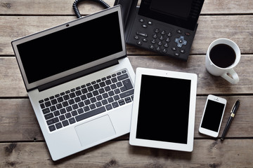 Open laptop with white digital tablet and smartphone on desk from above