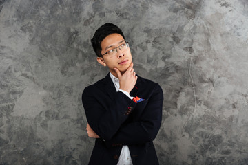 Canvas Print - Portrait of a pensive young asian man dressed in suit