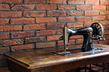 Old sewing machine with its wooden table near a wall of red bricks in Greece.