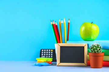 Wall Mural - A pile of books and stationery on a chalkboard background. Work desk, education, school.