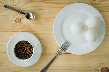 Raw egg on a plate and coffee beans in a cup