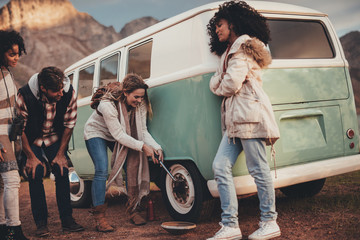 Wall Mural - Friends on road trip repairing tire puncture of van