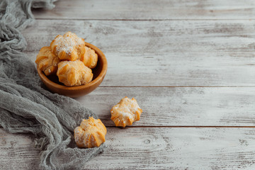 Wall Mural - Delicious homemade cakes and desserts. Cream profitroles with sugar powder on plate on white wooden background