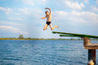 © Natali - sporty cute young boy jumps very high from pier and having fun on his vacation by the sea