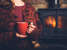 Woman In Red Jumper With Mug By Fire