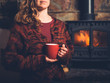 © LoloStock - Woman in red jumper with mug by fire
