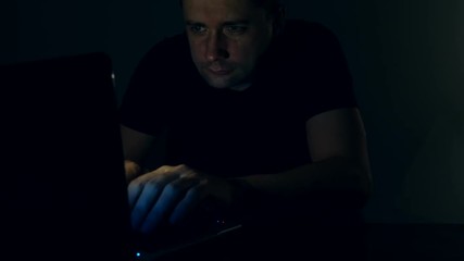 Man working with laptop at night. Programmer or hacker at work.